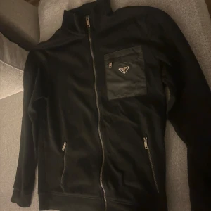 Prada tröja - Mycket fin prada zip tröja. Haft i cirka 2 år använt ett 20 tal gånger. Mycket bra skick med tanke på när jag köpte den. Såklart äkta.