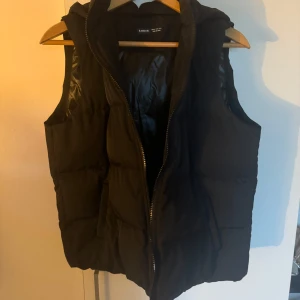 Svart dunväst från Shein - Snygg svart dunväst från Shein med dragkedja och huva. Perfekt för lager-på-lager under kyliga dagar. Västen har en stilren design och är lätt att matcha med olika outfits.