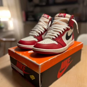 Nike Air Jordan 1 Retro High OG - Säljer ett par klassiska Nike Air Jordan 1 Retro High OG i rött, vitt och svart. Skorna har en ikonisk design med snörning och Nike-logga på sidan. Perfekta för sneakerheads som älskar tidlös stil. Använda endast 1 gång. Nypris runt 4000kr. 