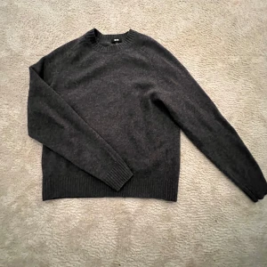 Mörkgrå tröja  - Säljer en stilren mörkgrå tröja från Uniqlo. Tröjan är långärmad och har en ribbad rund halsringning samt ribbade muddar vid ärmslut och nederkant. Perfekt för både lite kyligare och våriga dagar. Den är i storlek S och är hyfsat tunn, den är finstickad. Bara andvända ett fåtal gånger eftersom jag har vuxit ur den skickat är utmärkt,