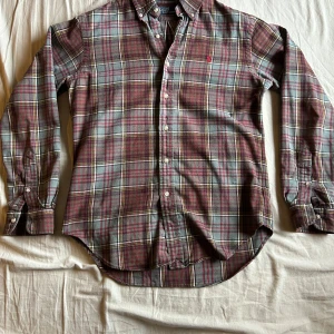 Ralph Lauren flanellskjorta - Säljer min Flanellskjorta från Ralph Lauren då den inte längre passar mig så bra. Den är i bra skick förutom att det är en slitning på framsidan men det är  ingenting man tänker på när man har på sig den. Kontakta gärna i Dm ifall du har några frågor!