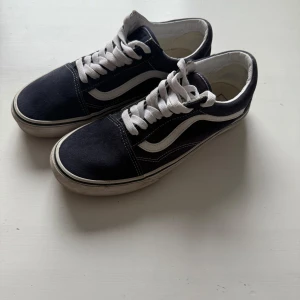Mörkblå sneakers från Vans - Säljer ett par klassiska mörkblå Vans sneakers med vit sula och vit snörning. Mycket fint skick sparsamt använda fåtalgånger! Skorna har den ikoniska vågiga sidodetaljen i vitt och en gummisula med rutmönster för bra grepp. Perfekta för en avslappnad stil. 
