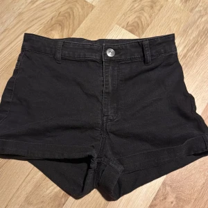 Svarta shorts från Hm - Snygga svarta shorts från H&M i stretchigt jeansmaterial. De har en klassisk design med knapp och dragkedja framtill samt fickor både fram och bak. Perfekta för en avslappnad stil.