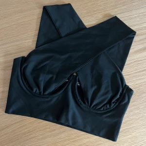 Svart topp - Snygg svart korsettliknande topp/linne med korsade axelband. 