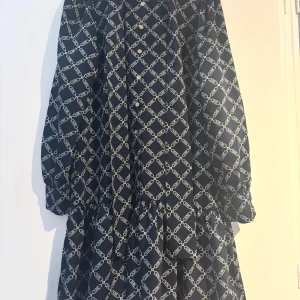 Michael kors klänning - Snygg klänning med ett geometriskt mönster i mörkblått och vitt. Klänningen har långa ärmar och knappar framtill. Perfekt för en stilren look.