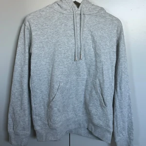 Grå hoodie - Säljer en klassisk grå hoodie med känguruficka och justerbar huva. Den har långa ärmar och ribbade muddar vid ärmslut och nederkant. ❤️