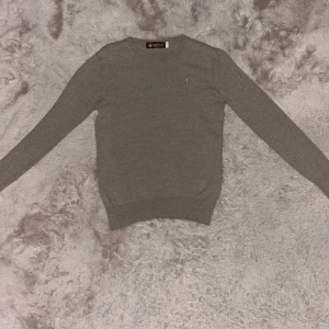 Stickad beige tröja från Morris - Säljer en stilren beige tröja från Morris i storlek S men den är lite liten så skulle rekommendera att köpa den om du är XS. Tröjan har en liten broderad detalj på bröstet och är tillverkad i ett mjukt material. Perfekt för en klassisk och elegant look. Den är använd tre gånger och är som ny. Tröjan är ganska tunn men är skön.