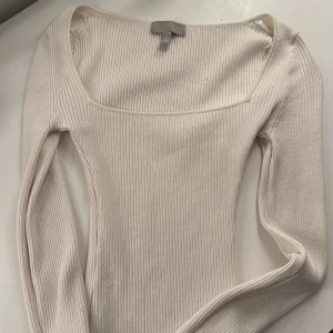 Beige ribbad topp från H&M - Säljer en stilren beige ribbad topp från H&M. Toppen har en fyrkantig halsringning och långa ärmar, perfekt för lager-på-lager eller som den är. Ett mångsidigt plagg för garderoben!