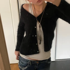 Svart kofta med knappar - Säljer en mysig svart kofta med knappar framtill. Perfekt för att hålla sig varm och stilren. Koftan har en klassisk design med långa ärmar och en mjuk känsla.