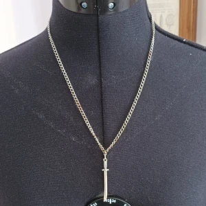 Halsband med svärdberlock - Unikt halsband med en detaljrik svärdberlock i silverfärg. Kedjan är tunn och elegant, vilket gör att berlocken verkligen står ut. Perfekt för att ge en edgy touch till din stil.