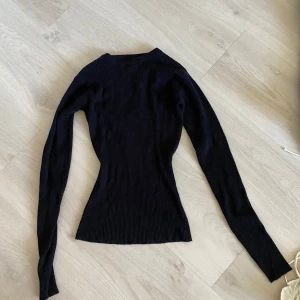 Svart ribbad tröja från NA-KD - Säljer en stilren svart ribbad tröja från NA-KD. Tröjan har en tight passform och långa ärmar, perfekt för en chic och enkel look. Passar utmärkt till både jeans och kjol. Perfekt för höst och vinter!