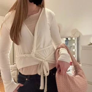Vit omlottkofta - Säljer en stilren vit omlottkofta med knytband i midjan. Koftan har långa ärmar och är perfekt för lager-på-lager-stil. Passar bra till både jeans och kjol.(Vet ej hur den ska knytas)🩷
