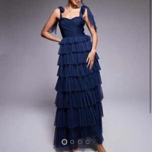 Lace & Beads svart klänning - HELT NY & slutsåld på hemsida. Elegant svart långklänning. Perfekt till bal och andra firanden framåt. 💓Den har lager av volanger och knytband med rosettdetalj. Säljer då det inte går att lämna tillbaka längre. Säljer för bra pris då prislapp sitter kvar och endast testad. Passar storlek 32-36 (storlek 34) OBS den är svart!
