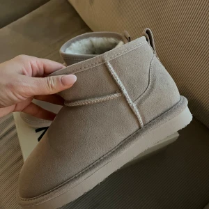 Beige boots från Bianco - Säljer ett par mysiga beige boots från Bianco. De är tillverkade i mocka och har en mjuk, fodrad insida för extra värme. Perfekta för kyliga dagar!