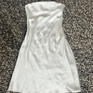 Vit axelbandslös satinklänning - Säljer en vit klänning i satin. Jättefin till sommaren och även perfekta studentklänningen🤍 Köpt i london, vet ej märket då jag klippt bort lappen inuti.  Aldrig använd!