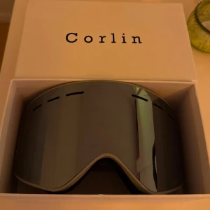 Skidglasögon från Corlin - Snygga skidglasögon från Corlin med en spegelblank lins och justerbart band. Knappt använda, köpta för 1500kr men säljer till bra pris då jag vill bli av med de. Box, förvaringspåse och tvättlapp till glasögonen medföljer. 