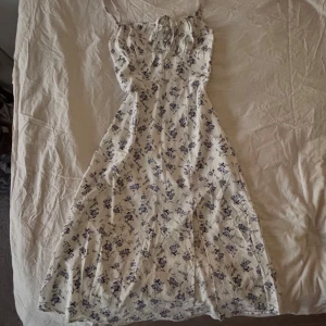 Blommig klänning med knytband - En fin blommig klänning som har dragkedja på sidan och snörning vid brösten. Det är även en slits på sidan. Säljer för att den blivit för liten. 