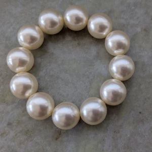 Pärlarmband med stora pärlor - Elegant armband med stora, glänsande pärlor i en klassisk vit nyans. Perfekt för att ge en sofistikerad touch till din outfit. Armbandet är elastiskt och passar de flesta handleder.