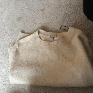 Beige stickad tröja från H&M - Mysig beige stickad tröja från H&M i storlek L. Tröjan har rund halsringning och är långärmad, perfekt för lager-på-lager under kyliga dagar. Enkel och stilren design som passar till det mesta. Skulle säga att den är som en S-M. 