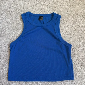 Blå ribbad linnetopp  - Snygg blå ribbad linnetopp från SHEIN med croppad passform. Toppen är ärmlös och har en sportig, enkel design som passar perfekt till jeans eller kjol. Perfekt för varma dagar eller lager på lager-stil. Storlek xs🥰