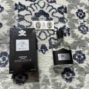 Creed Aventus Eau de Parfum 100ml - Creed Aventus Eau de Parfum 100ml med elegant svart och silver kartong. Flaskan är genomskinlig med svart etikett och silverdetaljer, samt svart kork. Lyxig och ikonisk doft för dig som vill sticka ut.