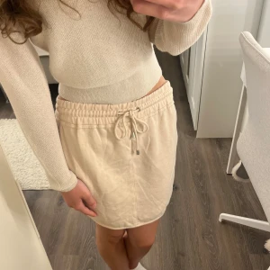 Beige kortkjol från Bik Bok Balance - Supermjuk beige kortkjol från Bik Bok Balance med elastisk midja och snörning framtill. Kjolen är i sweatshirt-material och har en avslappnad vibe, perfekt för chill dagar💗