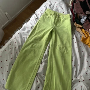 Limegröna wide jeans från Monki - Säljer ett par limegröna jeans från Monki med breda ben och klassisk femficksdesign. Byxorna har hög midja och är tillverkade i bomull. Perfekta för dig som vill sticka ut med en färgklick i garderoben!