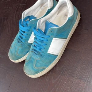 Blå och vita sneakers från Valentino - Snygga sneakers från Valentino i blå mocka och vitt skinn med blå skosnören storlek 43 men passar 42 box o dustbags ingår. Priset är it skrivet i sten