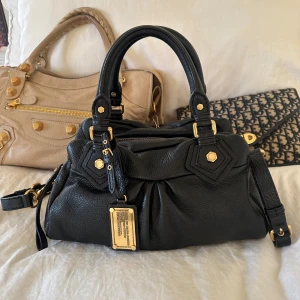 Snyggaste svarta Q Classic Baby Groove väskan! - Säljer denna billigare via min vinted pga lägre avgifter @juliavallberg 🖤Snyggaste svarta handväskan i äkta läder från Marc by Marc Jacobs. Den ikoniska modellen Q Classic Baby Groove! En populär och eftertraktad vintagemodell med gulddetaljer och dubbla handtag. Helt som ny, otroligt välbevarad.  Mått: 34x18x12 cm (undersida) Kan hämtas hemma hos mig i Nacka eller skickas 🤍