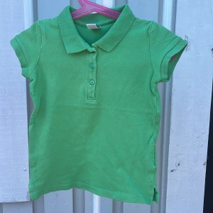 Grön pikétröja Zara Kids 104 - Snygg grön pikétröja från Zara Kids i storlek 104. Klassisk krage, tre knappar framtill och korta ärmar. Perfekt för vår och sommar, tillverkad i mjuk bomull som är skön att ha på sig hela dagen.