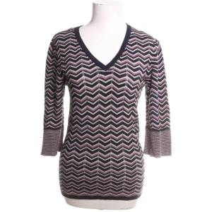 Mönstrad tröja från Saint Tropez - Snygg stickad tröja från Saint Tropez med zigzag-randigt mönster i svart och lila toner med inslag av glitter. Tröjan har v-ringning och trekvartsärm i bomull. Perfekt för dig som gillar unika detaljer och lite retro stil.