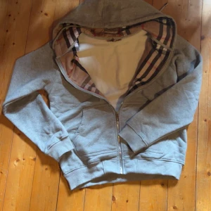 Grå hoodie från Burberry med dragkedja - Snygg grå hoodie från burberry. Säljer den då jag fick den i fel storlek och det är en lång process att skicka tillbaka den. Priset kan diskuteras vid snabb affär