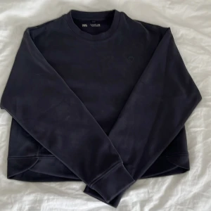 Svart sweatshirt från Zara med hjärtdetalj - En svart sweatshirt från Zara med rund hals och en liten hjärtdetalj på bröstet. Tröjan har långa ärmar och är gjord i mjuk bomull, perfekt för en kylig höstdag. Oanvänd, bara testad.