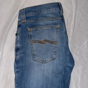  Nudie Jeans, W30 L32 - Ett  par riktigt fetta blå jeans från Nudie, med snygga kontrastsömmar och ikonisk bakficka. Modellen har slim fit som passform. Tillverkade i cool look. 