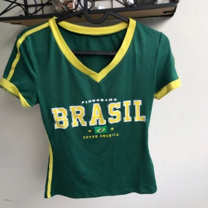 Grön Brasil t-shirt  - Snygg grön t-shirt, v-ringad vid halsen. Jätte snygg att ha low waist byxor/jeans/shorts till. Det är lite strech i men passar bäst på XS men passar S oxå💕