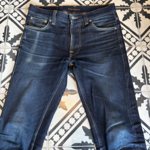 Nudie Jeans, Lean Dean True Selvage  - Ska sälja mina Nudie Jeans, Lean Dean True Selvage då jag har växt ut dem. Köpte de nya på Nudie Butik för 2000 kr. Har fått sköna slitningar under åren, dock även två hål i högerfickan(se bild 5)