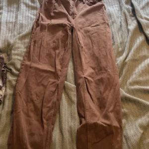 Bruna raka byxor  - Säljer ett par bruna byxor i mjuk bomull med raka ben och klassiska fickor både fram och bak. Perfekta för en chill och avslappnad stil. Passar dig som gillar enkel och stilren look.