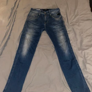 Blå Replay jeans Anbass , midwaist, 29/32 - Säljer ett par snygga blå jeans från Replay i modellen 29/32. Jeansen har klassisk femficksdesign, lätt slitna detaljer framtill och raka ben. Perfekta för dig som gillar en tidlös look med lite edge. Materialet är mjukt och följsamt jeans. Storlek 29/32. Indirekt oanvända 