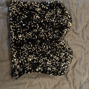 Svart paljett-tubtopp från ONLY - Glittrig svart tubtopp från ONLY, täckt med massor av svarta paljetter. Storlek small, tight passform, perfekt för festliga tillfällen! Endast använd en gång.