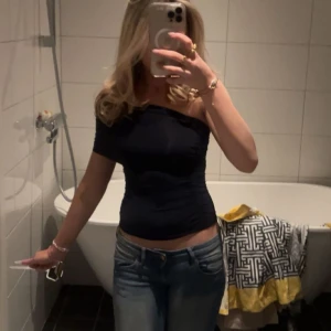 Topp från Zara - Säljer en marinblå, tight och croppad one shoulder topp med snygga rynkade detaljer. Toppen är ärmlös på ena sidan och har en axelrem på andra, vilket ger en cool asymmetrisk look. Perfekt att styla med jeans eller kjol för en trendig outfit.