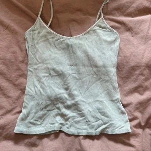 Ljusgrön ribbad linnetopp - En enkel och stilren ljusgrön linnetopp med smala axelband och v-ringad hals😍. Toppen är ribbad och har en mjuk, stretchig känsla som gör den superbekväm. Perfekt att matcha med jeans eller kjol för en chill look. Storlek M men jag som har S kan ha den!❤️
