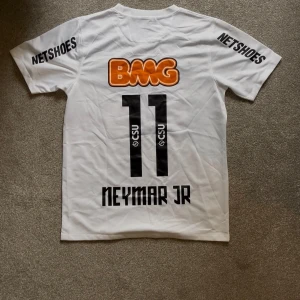 Santos Neymar Jr fotbollströja  - Santos hemmatröja med Neymar Jr och nummer 11 på ryggen. Klassiska sponsortryck som BMG och Netshoes, samt klubbmärke på bröstet. Autentisk Nike-tröja, Skick 8/10, storlek Xs-S