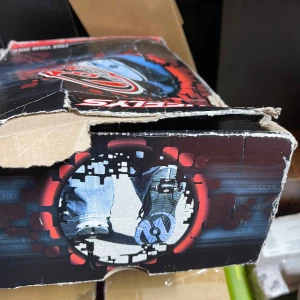 Svarta och vita Heelys sneakers med hjul - Coola Heelys sneakers i svart och vitt med röda detaljer och hjul i sulan. Skorna har snörning, rund tå och tryckt textmönster på sidorna. Perfekta för dig som vill rulla fram med stil! Klassisk Heelys-logga på sidan och tungan.