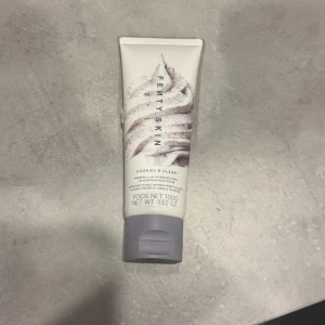 Fenty Skin Cookies N Clean ansiktsskrubb - Fenty Skin Cookies N Clean är en intensiv lermask och ansiktsskrubb i en vit tub med grått lock. Produkten är framtagen för att rengöra porer och motverka pormaskar. Tuben innehåller 100g och har en snygg swirl-design på framsidan. Har använts några gången men är nästan som ny