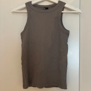 Grå ribbad linnetopp från Pieces - Säljer en stilren grå ribbad linnetopp från Pieces. Toppen är ärmlös med breda axelband och rund halsringning. Perfekt för lager-på-lager eller att bära som den är. Enkel och clean design som funkar till allt. Aldrig använd.