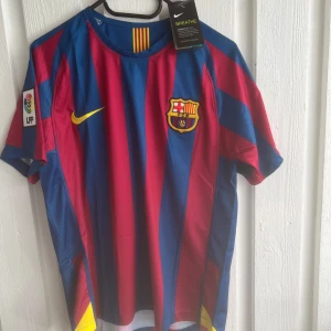 FC Barcelona Messi 30 Nike matchtröja - Säljer en klassisk FC Barcelona fotbollströja med Messi 30 på ryggen. Tröjan är randig i blått och rött med gula detaljer, klubbmärke på bröstet och LFP-patch på ärmen. Tillverkad i lätt och ventilerande material, perfekt för dig som älskar Barca och Messi.