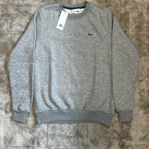 Lacoste Sweatshirt  - Lacoste sweatshirt i grym kvalité. Fick den som present från min farbror som köpte flera på stor rea utomlands – kvitto finns ej. QR-koden på insidan går direkt till Lacostes hemsida och den är helt ny. Superren modell, passar till allt.  Pris kan diskuteras