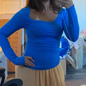 Blå långärmad topp med fyrkantig ringning - Säljer en klarblå långärmad topp med snygg fyrkantig ringning. Modellen är tight och sitter figurnära, perfekt för dig som gillar en enkel men ändå trendig look. 