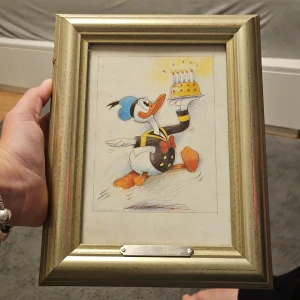 Inramad Reproduktion - Kalle Anka - Cool inramad reproduktion av Lasse Åberg med Kalle Anka som bär en tårta. Perfekt för dig som älskar popkultur, Disney och konst med humoristisk twist. Passar utmärkt i ungdomsrum eller som unik present till någon som gillar serier och klassiska figurer.