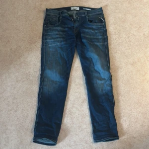 Blå Replay jeans, midwaist, storlek 30/30 - Säljer ett par snygga blå jeans från Replay i modellen midwaist. Jeansen har klassisk femficksdesign, lätt slitna detaljer och raka ben. Materialet är jeans och passformen är normal med en stilren look. Perfekta för dig som gillar en tidlös stil. 